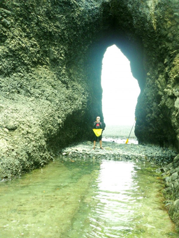 Coastal rock archway with person standing in the shoals